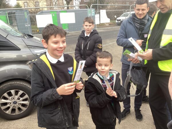Students receiving seed pencils following a site visit to a timber frame classroom building in construction